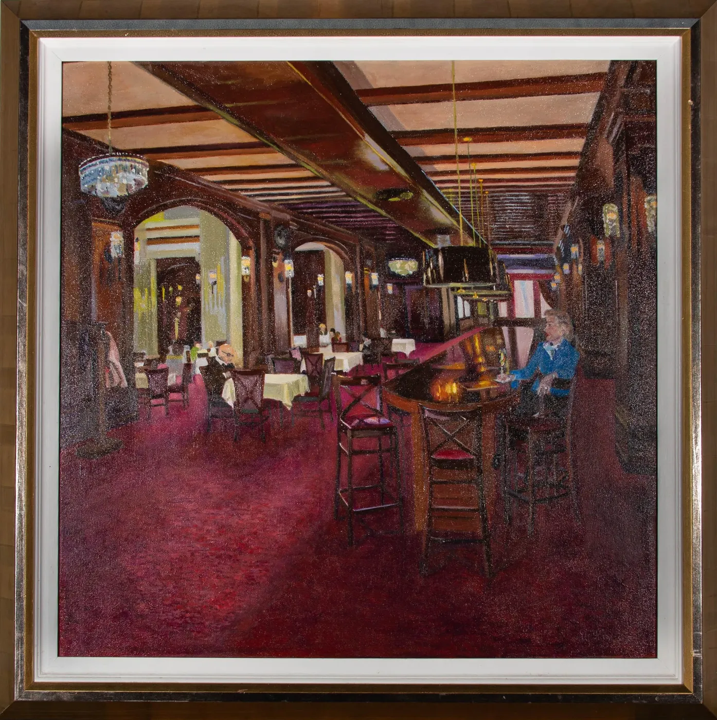 A deep red hotel bar seen across an expanse of carpet: dark beams, a chandelier, white-clothed tables, and one figure in blue alone at the bar.