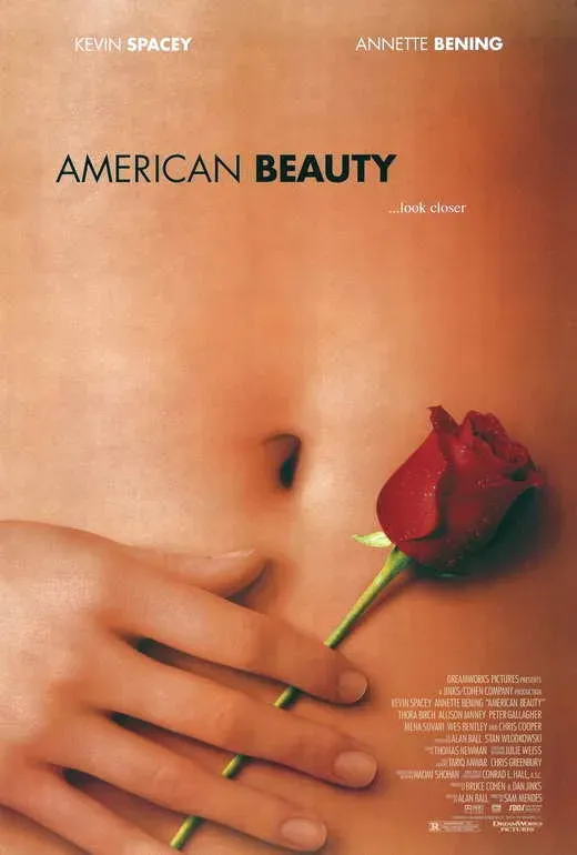 A hand holding a single red rose against bare skin.